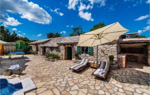 a stone patio with chairs and an umbrella at Gorgeous Home In Zelengrad With Kitchen in Zelengrad
