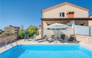 a swimming pool with chairs and an umbrella next to a house at Gorgeous Home In Lovrecica With Kitchen in Lovrečica