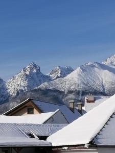 a view of snow covered mountains from the roofs of houses at Apartman Lastovicka in Stará Lesná