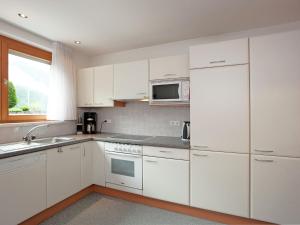 a white kitchen with white cabinets and a microwave at Apartment near the ski area in Vandans in Vandans