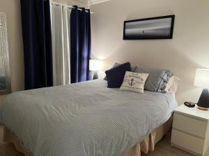 1 dormitorio con 1 cama con cortinas azules y espejo en Condos Memphrémagog, en Magog-Orford