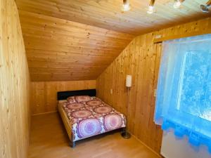 uma pequena cama num quarto de madeira com uma janela em Holiday apartment in Salchau near ski area 