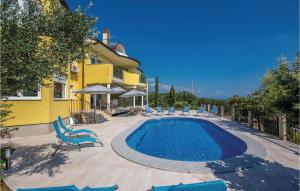 a swimming pool in front of a yellow house with chairs at Awesome Home In Kostrena With Wifi in Kostrena