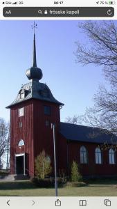 a red barn with a black roof and a steeple at Vackert hus i Fröseke närmare naturen in Fröseke