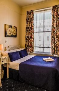 um quarto com uma cama grande e uma janela em Blades Hotel em Londres
