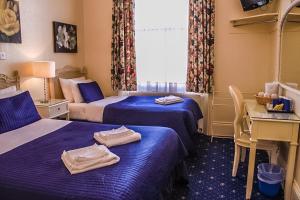 um quarto de hotel com duas camas com toalhas em Blades Hotel em Londres
