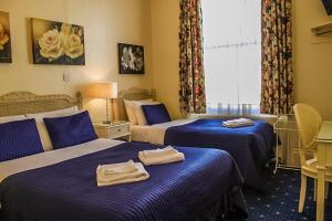 a hotel room with two beds with towels on them at Blades Hotel in London