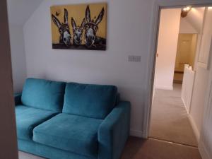 un sofá azul en una sala de estar con una pintura en la pared en The Wheatsheaf Inn en Atherstone