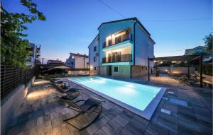 einen Pool mit zwei Stühlen und ein Haus in der Unterkunft Lovely Apartment In Zadar With Heated Swimming Pool in Zadar
