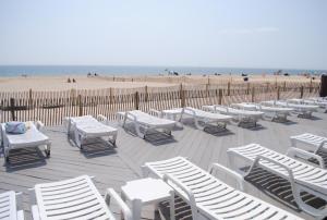 a bunch of white chairs and tables on a beach at Windswept Motel in Point Pleasant Beach