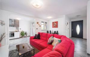 a red couch in a living room with a table at Nice Apartment In Boljevici With Wifi in Kršan