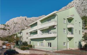 a green building with a mountain in the background at Nice Apartment In Omis With House Sea View in Omiš