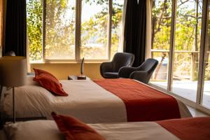 two beds in a room with two chairs and a window at Casa de Mar Hotel And Villas in El Sunzal