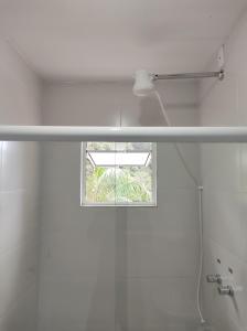 a white bathroom with a window and a shower at Suíte na Montanha in Trindade