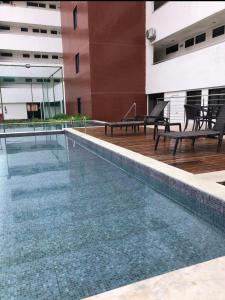 a swimming pool in a building with two benches at Apartamento na Prata in Campina Grande