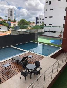 a balcony with a table and chairs and a swimming pool at Apartamento na Prata in Campina Grande