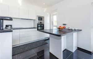 a kitchen with white cabinets and a black counter top at Three-Bedroom Holiday Home In Brodarica in Brodarica +24 photos