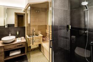 ein Bad mit einer Dusche, einem Waschbecken und einem WC in der Unterkunft Apartments Villa Gardena - Gardenahotels in Wolkenstein in Gröden