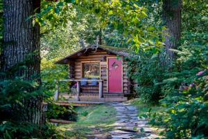 a small cabin with a pink door in a forest at Hope Alaska's Bear Creek Lodge in Hope
