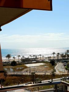 a view of a beach with palm trees and the ocean at Apartamento con vistas al mar in Alicante