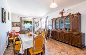 a dining room with a table and a large wooden cabinet at Stunning Apartment In Gruda With 2 Bedrooms And Wifi in Molunat