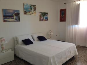 a white bedroom with a white bed with blue pillows at Villataty B&B in Castrignano del Capo