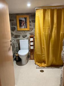 baño con aseo y cortina de ducha amarilla en BezerreiraComVida-O refúgio do monte en Bezerreira