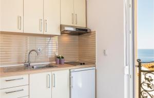 una cocina con armarios blancos y fregadero en Beautiful Apartment In Krvavica With Kitchen, en Krvavica