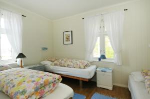 a bedroom with two beds and two windows at Nyksund Apartments Marihaugen in Nyksund