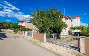 a fence in front of a house with a tree at 2 Bedroom Awesome Apartment In Povljana in Povljana