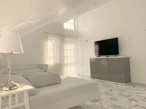 a white living room with a couch and a tv at F10 APARTMENTS Roth in Pfaffenhofen an der Roth