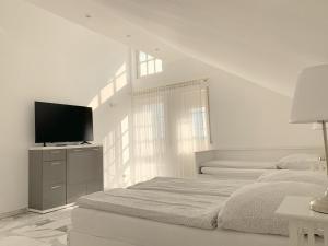 ein weißes Schlafzimmer mit einem Bett und einem Flachbild-TV in der Unterkunft F10 APARTMENTS Roth in Pfaffenhofen an der Roth