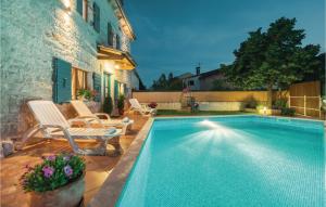 a swimming pool with two chairs next to a house at Holiday Home Orbanici Orbanici Ii in Orbanići +29 photos