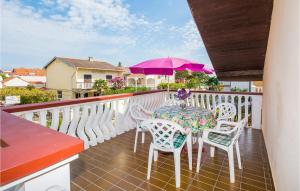 balcón con mesa, sillas y sombrilla púrpura en Awesome Home In Sabunike-privlaka With Kitchen, en Nin