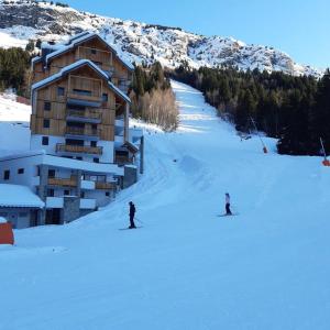 two people skiing in the snow in front of a building at Superbe appartement de 62 m2 au pied des pistes in Oz