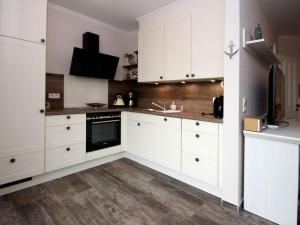 a white kitchen with white cabinets and a television at Ferienhaus mit Garten in Neßmersiel