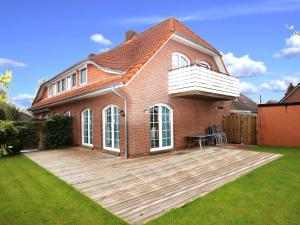 ein Haus mit einer Holzterrasse im Hof in der Unterkunft Semi-detached house Schwittersum, Dornum in Dornum