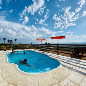 a swimming pool with people in the water at Cabañas PAIGÜEN in Villa Yacanto