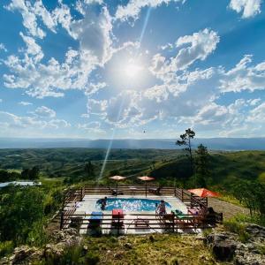 a swimming pool on top of a hill with the sun in the sky at Cabañas PAIGÜEN in Villa Yacanto