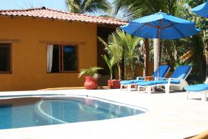 a swimming pool with two chairs and an umbrella at Casa Kaukan in Zihuatanejo
