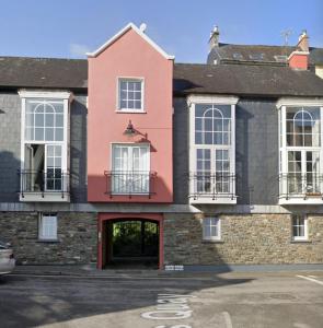 a pink house with white windows and a parking lot at Heart of Kinsale in Kinsale