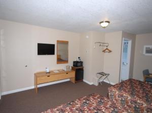 Habitación de hotel con cama, escritorio y TV. en Wayside Motel, en Saint Ignace