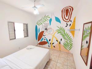 a bedroom with a white bed and a mural on the wall at Casa Mar Peruíbe in Peruíbe