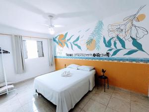 - une chambre avec un lit et une peinture murale dans l'établissement Casa Mar Peruíbe, à Peruíbe