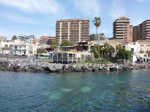 a group of people standing on rocks near the water at B&B Casa Valeria in Catania