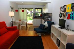 sala de estar con sofá rojo y cocina en Acoteias Studio by be@home, en Albufeira