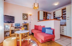 uma sala de estar com um sofá vermelho e uma mesa em Amazing Apartment In Novi Vinodolski With Kitchen em Novi Vinodolski