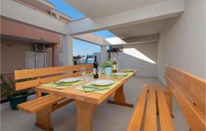 - une table en bois avec deux bancs et une bouteille de vin dans l'établissement Cozy Apartment In Baska Voda With Kitchen, à Baška Voda