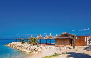 a group of huts on a beach near the water at Beautiful Apartment In Njivice With Kitchen in Njivice