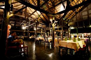 a restaurant with tables and chairs and a man sitting in a room at Lampang River Lodge - SHA certified in Lampang